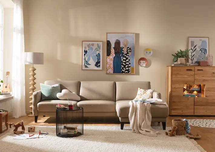 Beiges Sofa mit Couchtisch, Sideboard, Stehlampe, Decke und Spielzeug auf Teppich